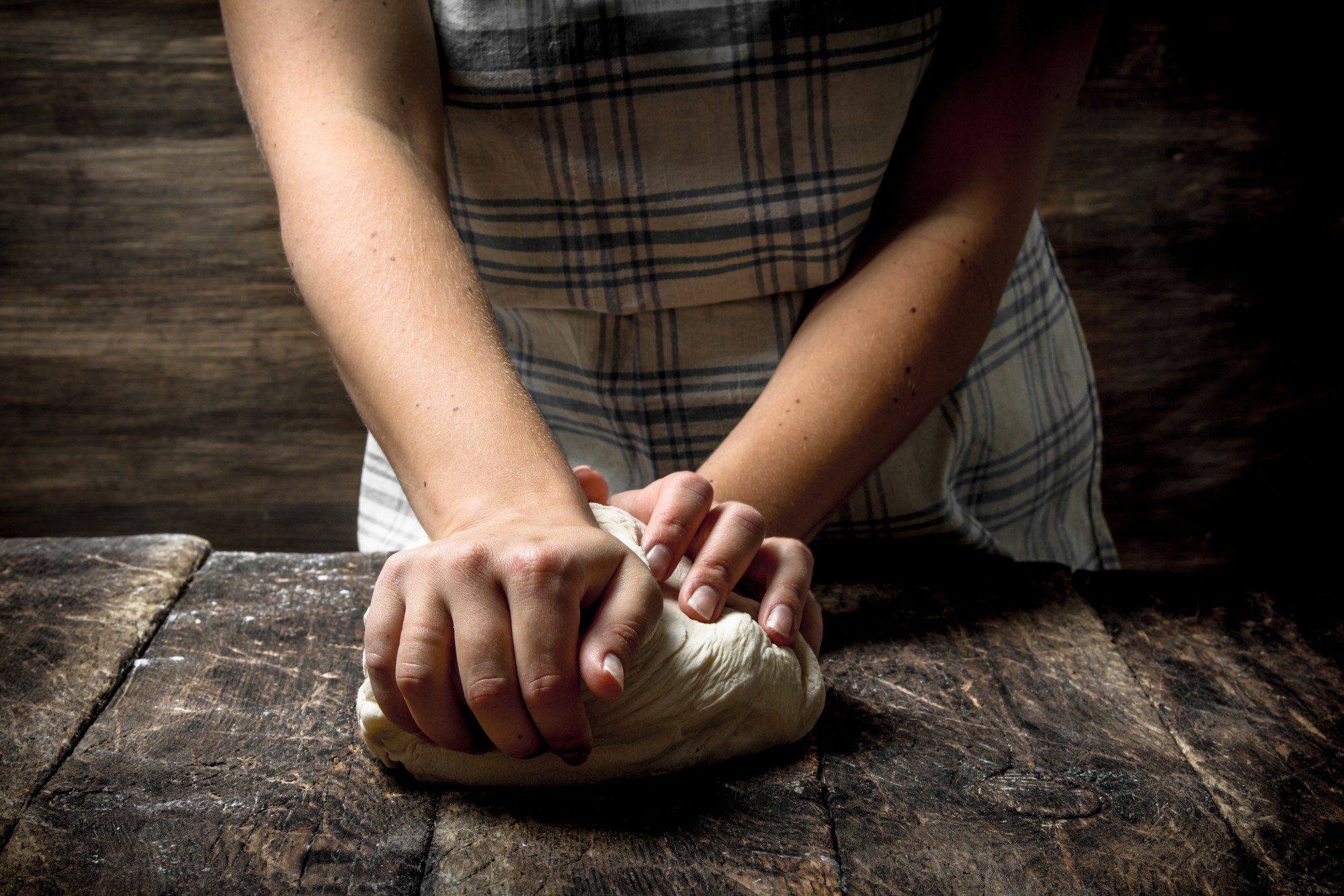 Hands kneading dough on wooden table